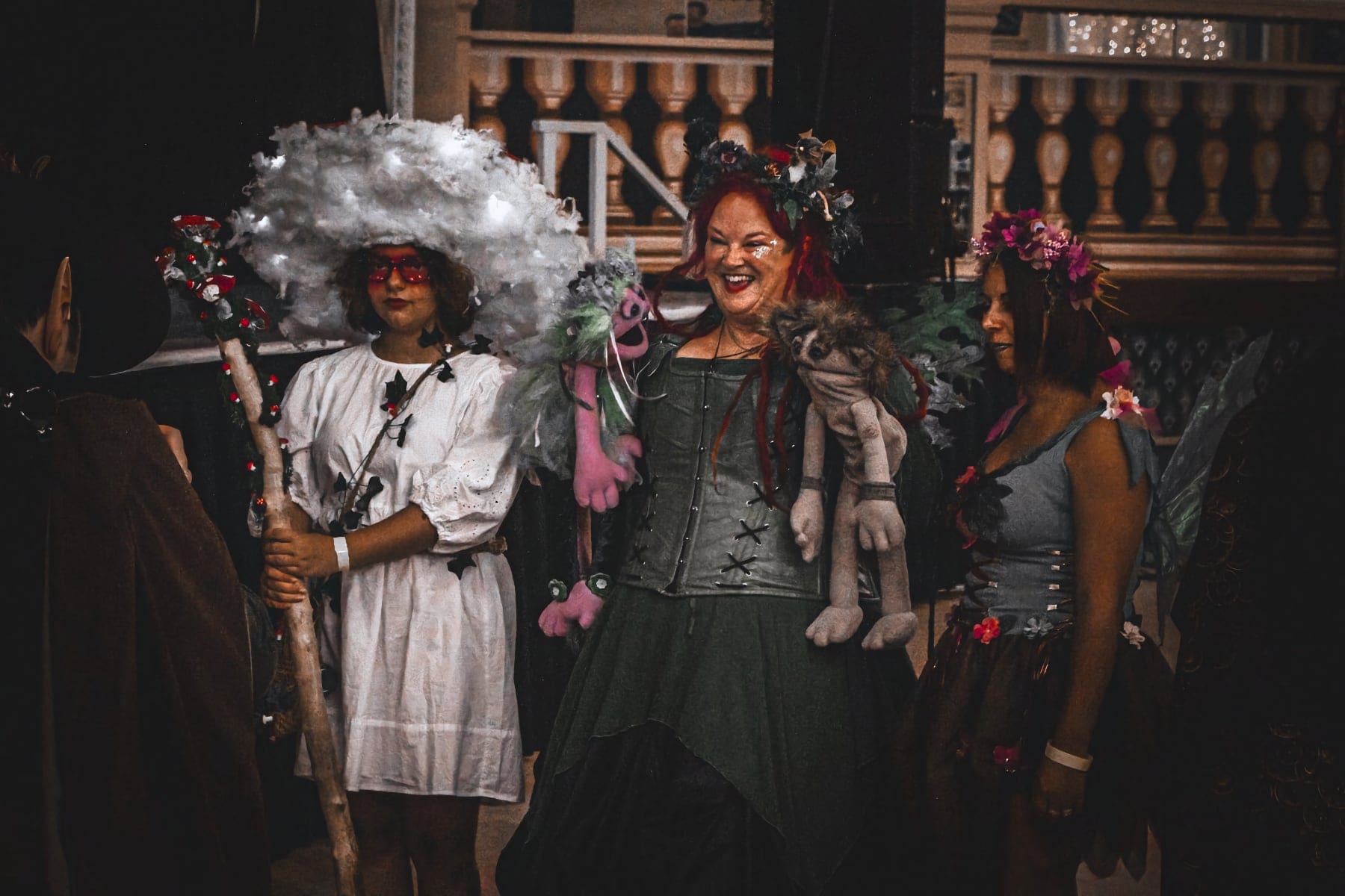 Attendees in elaborate fairy and fantasy costumes, including one with a cloud hat, enjoy the event together.