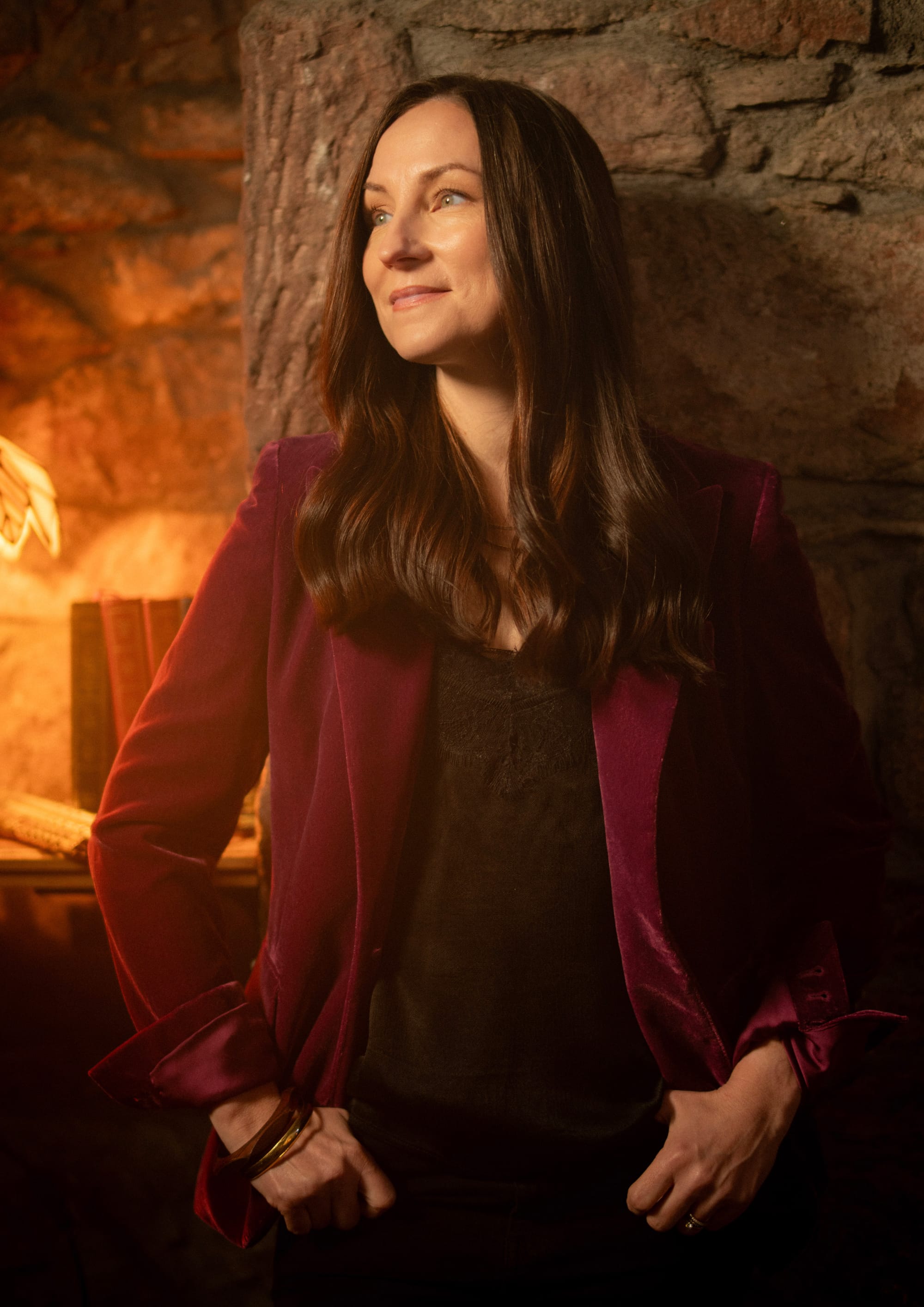 Julie Fowlis in a red velvet jacket, photographed against a stone wall