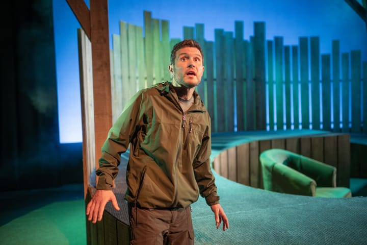 Jordan Young on stage in Man’s Best Friend, green-blue light and timber set.