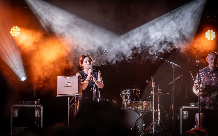 Julie Fowlis performing on stage under dramatic orange stage lighting