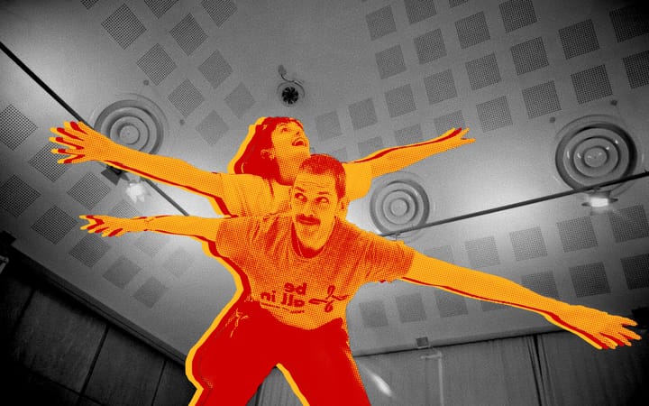 Two young Light the Blue performers, arms outstretched, composited against the Music Hall interior