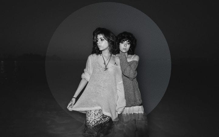 Black and white photo of twin sisters Venice and Belle Herrera standing back to back.
